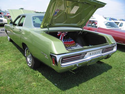 2001 Ford Crown Victoria - Rear view of a green 1970 Dodge Charger SE sedan parked on grass with its trunk open.