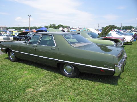 2001 Ford Crown Victoria - A green sedan is parked on the grass at an outdoor car show with several other vehicles visible.