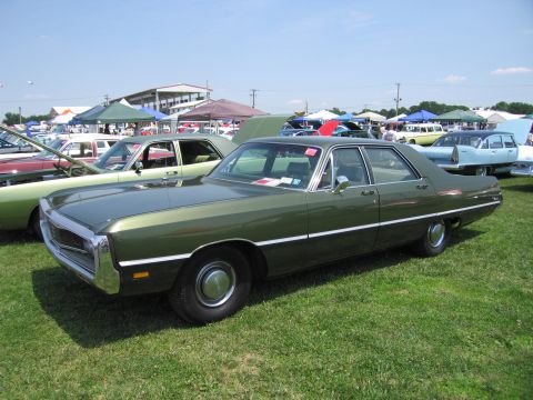 2001 Ford Crown Victoria - A green sedan is displayed at an outdoor event with other vehicles and tents visible.