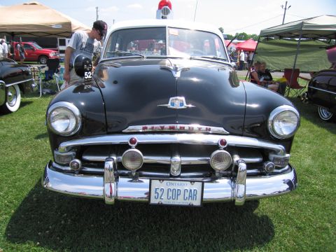 2001 Ford Crown Victoria - This 1952 Plymouth Cop Car is displayed at an outdoor event, its distinctive front grille and "52 COP CAR" license plate.