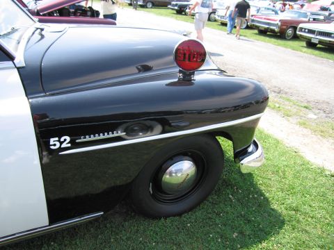 2001 Ford Crown Victoria - A vintage police car with a "STOP" light is parked on grass with other vehicles in the background.