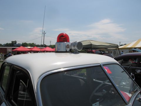 2001 Ford Crown Victoria - A vintage police car is seen with its emergency lights and siren mounted on the roof, parked at an outdoor event.