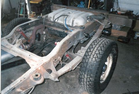 1983 Ford Bronco - The chassis of a vehicle, including the frame, fuel tank, and a tire, is shown in this image.