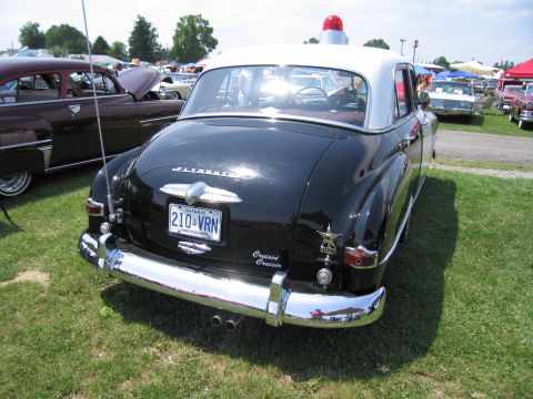 2001 Ford Crown Victoria - This vintage Plymouth police car, identified as a 'Cruiser', is displayed outdoors with other vehicles.