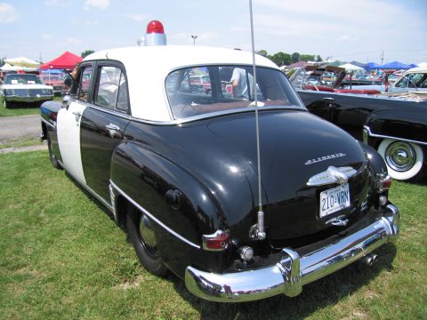 2001 Ford Crown Victoria - This vintage police car has a two-tone black and white paint scheme and a classic siren light.