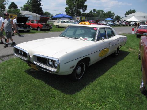 2001 Ford Crown Victoria - A white taxi sedan from the 1970s is parked on a grassy field with other vehicles in the background.