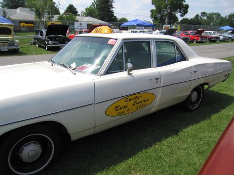 2001 Ford Crown Victoria - This taxi sedan has a yellow oval decal on its side door and a yellow taxi light on the roof.