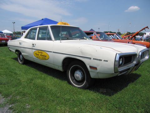 2001 Ford Crown Victoria - A white taxi sedan is parked on grass with other vehicles and tents in the background under a blue sky.