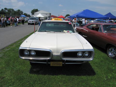 2001 Ford Crown Victoria - A white taxi with a yellow "TAXI" sign on top is parked on grass at an outdoor event.