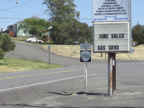 1993 Ford Bronco - A white coupe is parked near a road with directional and business signage visible.