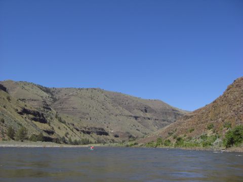 1993 Ford Bronco - A lone kayaker navigates a wide river, surrounded by arid, mountainous terrain under a clear blue sky.