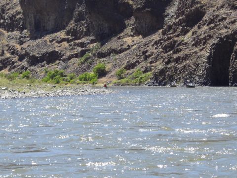 1993 Ford Bronco - A scenic view of a river flowing by a rocky cliff face with two boats in the distance.