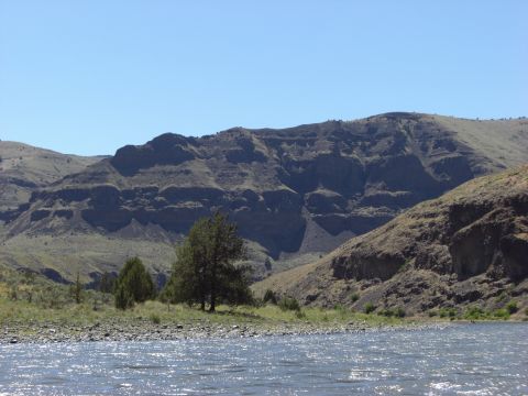 1993 Ford Bronco - A wide river flows through a valley with mountains in the background under a clear blue sky.