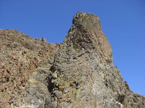 1993 Ford Bronco - A geological formation of layered rock stands against a bright blue sky.