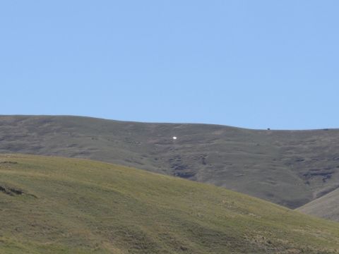 1993 Ford Bronco - A lone vehicle is visible on a distant hilltop, dwarfed by the vast landscape.