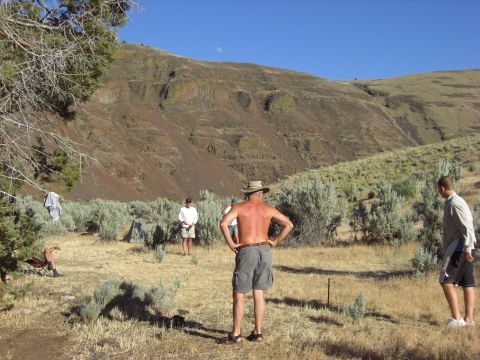 1993 Ford Bronco - Several people are gathered in a dry, open area with rolling hills and sparse vegetation under a clear blue sky.