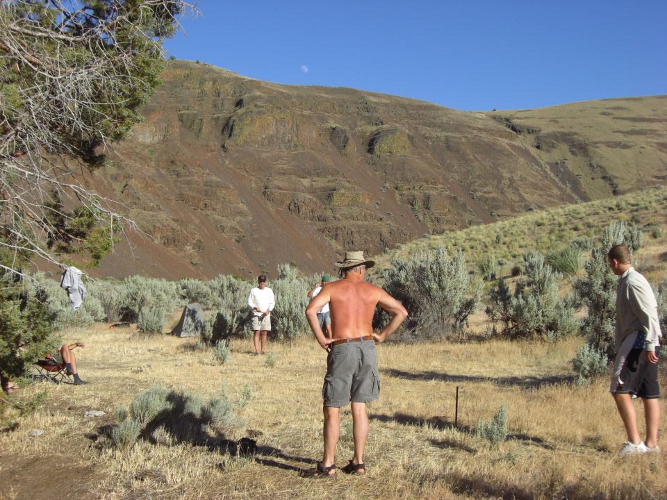 People gathered in a dry, hilly landscape with sagebrush and a blue sky