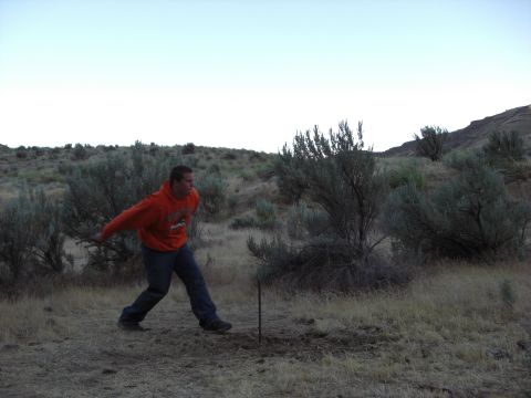 1993 Ford Bronco - A man in an orange hoodie is outdoors in a dry, brushy landscape, possibly throwing an object.