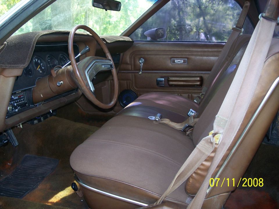 Brown interior of a 1977 Ford Ranchero with a cracked dashboard and worn seats