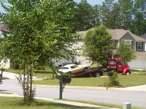 1979 Chevrolet Camaro - A cream-colored coupe, likely a 1977 model, is being towed by a red truck in front of a suburban house.