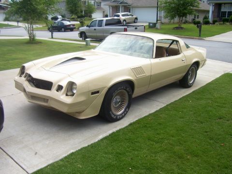 1979 Chevrolet Camaro - A tan coupe with a hood scoop sits on a concrete driveway, with a suburban neighborhood in the background.
