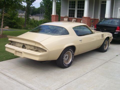 1979 Chevrolet Camaro - A tan coupe with a spoiler and aftermarket wheels is parked in a driveway next to a black SUV.