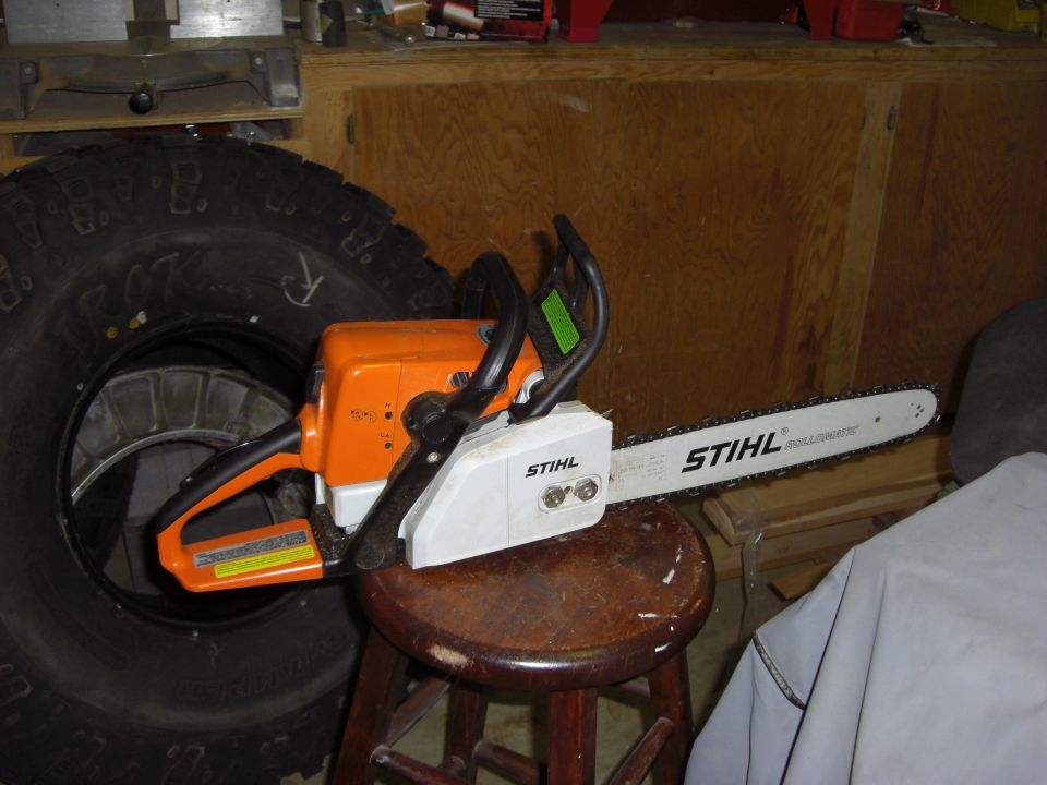 Stihl chainsaw on a wooden stool next to a large tire
