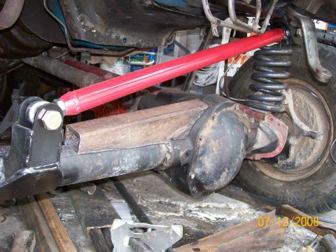 1984 Ford Bronco - Close-up view of a modified rear axle and suspension system, a bright red adjustable control arm.