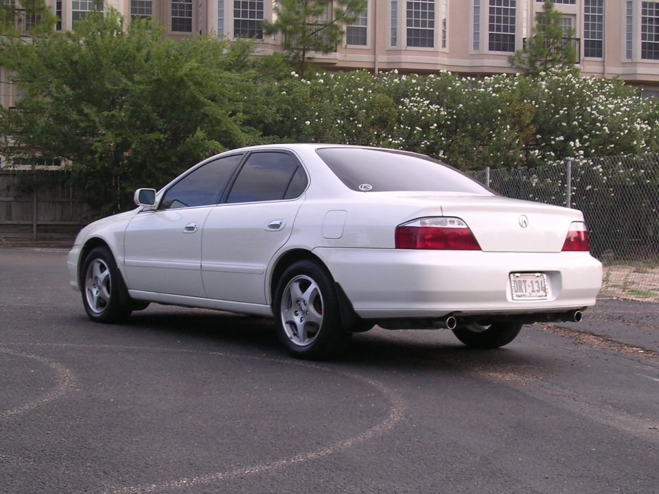 White 2003 Acura TL parked on asphalt, rear view. Building and trees in background