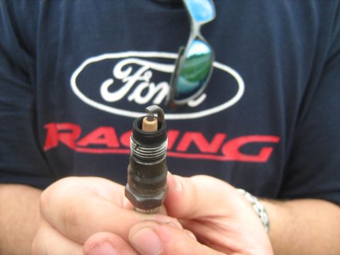 1988 Mercury Grand Marquis - A spark plug is held up in front of a Ford Racing t-shirt and sunglasses.