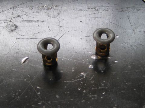 1996 Ford Bronco - Two grommets with brass bases and gray plastic tops are shown on a work surface.