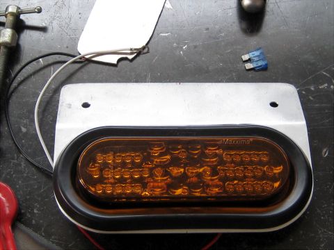 1996 Ford Bronco - A close-up view of an aftermarket oval amber LED light, possibly for a trailer, with wiring and a fuse shown.