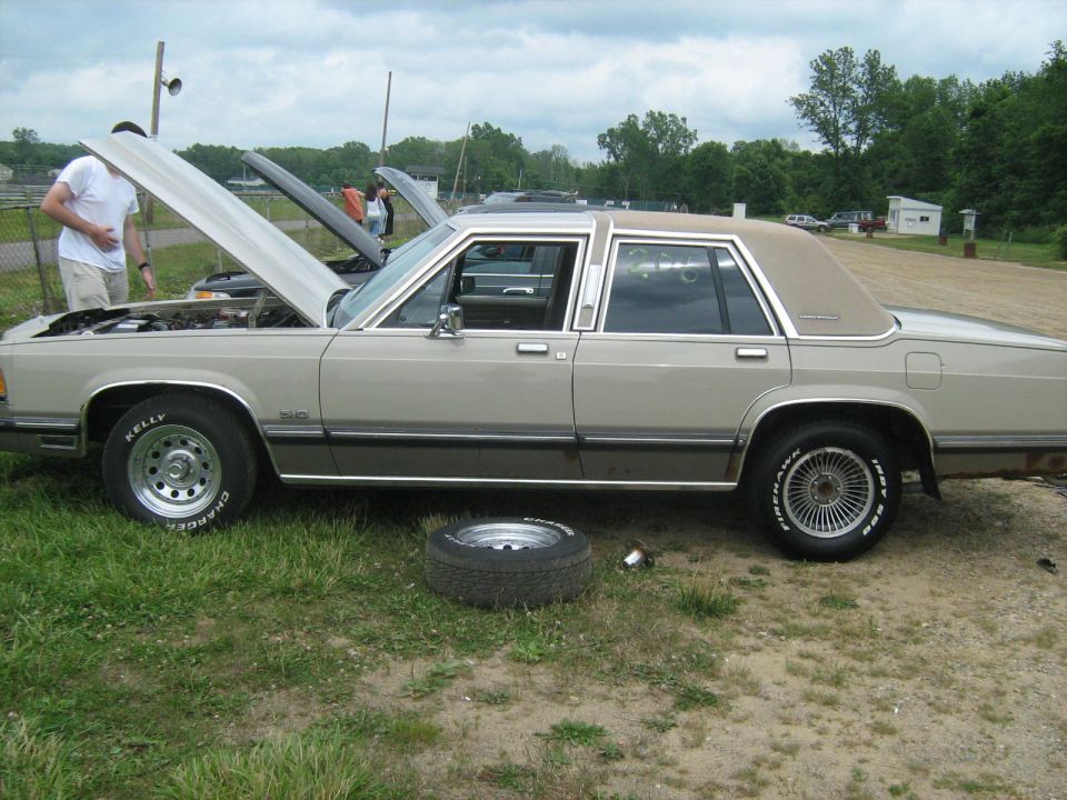 1988 Mercury Grand Marquis sedan, tan and brown, hood open, spare tire on ground