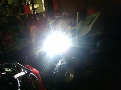1995 Ford Bronco - An ATV is parked indoors with its bright headlight illuminated.