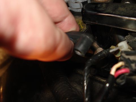 2000 Ford Crown Victoria - A hand is shown disconnecting a spark plug wire from an engine component, with some text visible on a yellow label.
