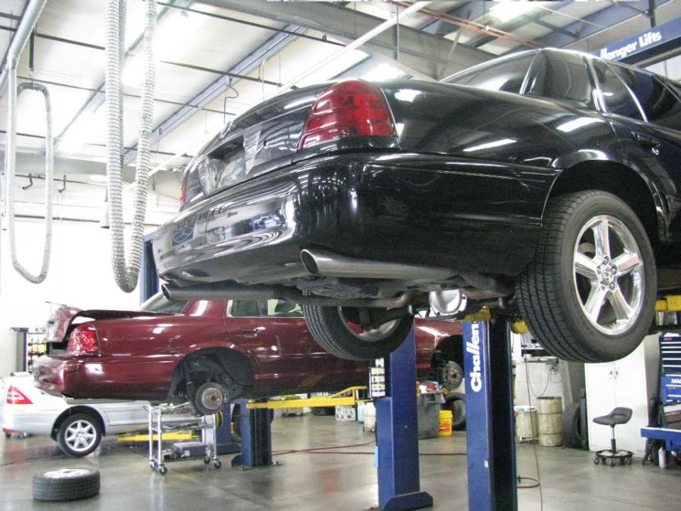 Black Mercury sedan on a hydraulic lift in an auto repair shop.