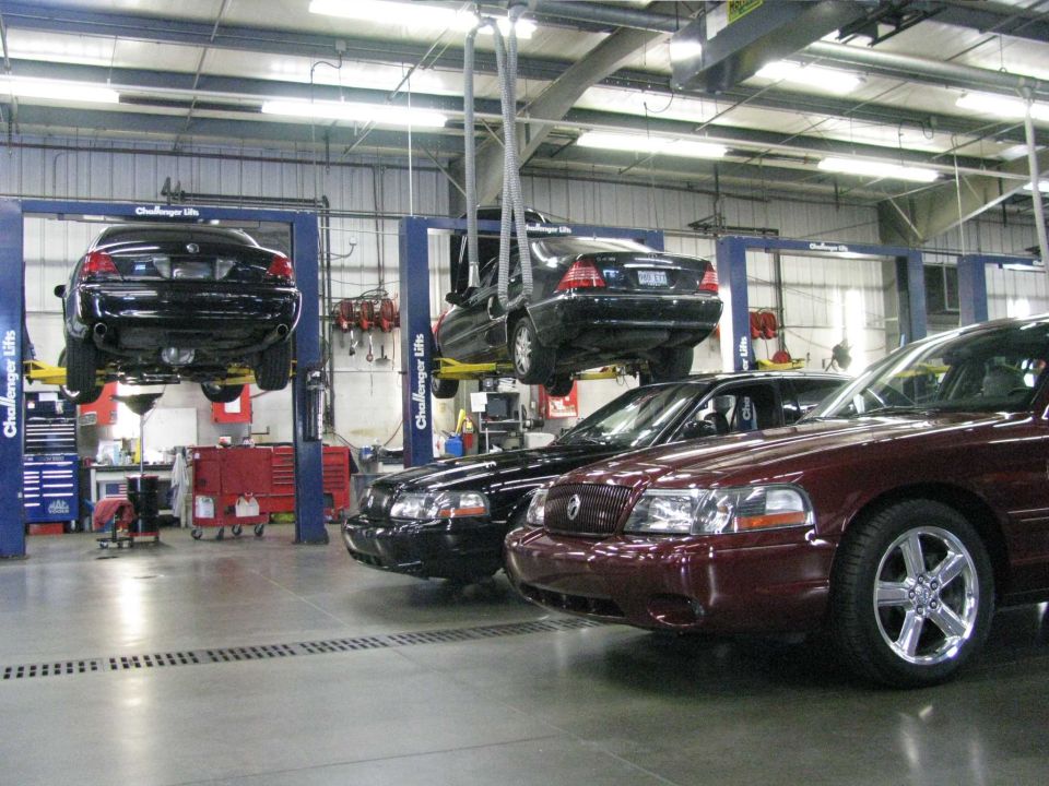 Maroon 2003 Mercury Marauder in a garage with a black sedan on a lift.