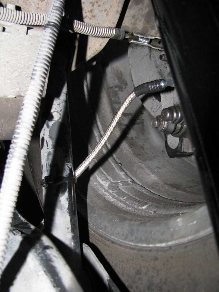 Braided metal brake line secured with zip tie to vehicle component.