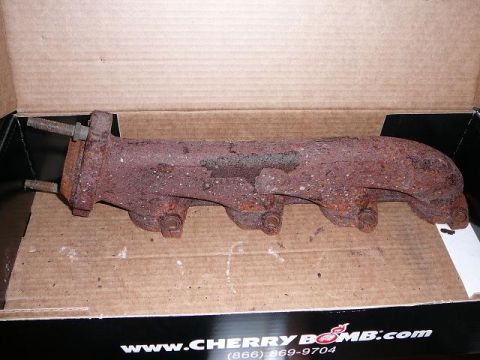 1997 Mercury Grand Marquis - This rusty exhaust manifold is shown in a box, with website information visible on the box's edge.