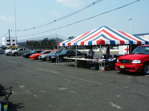 2001 Mercury Grand Marquis - Photo of cars parked beside a red-white-and-blue striped tent and bleachers at an outdoor car event.