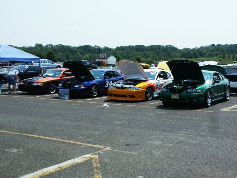2001 Mercury Grand Marquis - Several Ford Mustangs are displayed with their hoods open at a car show.
