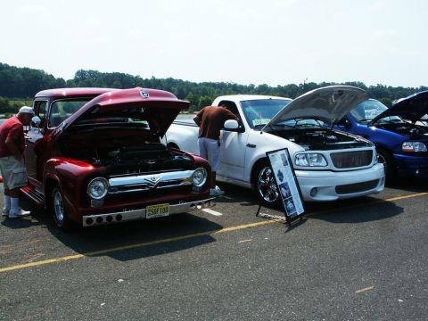 2001 Mercury Grand Marquis - Photo of a customized red Ford F-100 and a white Ford truck with hoods open at a car show.