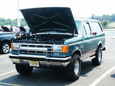 2001 Mercury Grand Marquis - A dark green Ford Bronco is parked with its hood up, showing the engine bay.