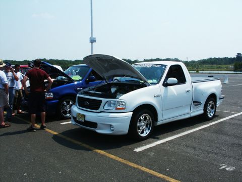 2001 Mercury Grand Marquis - A white pickup truck is displayed at a car show with its hood open.