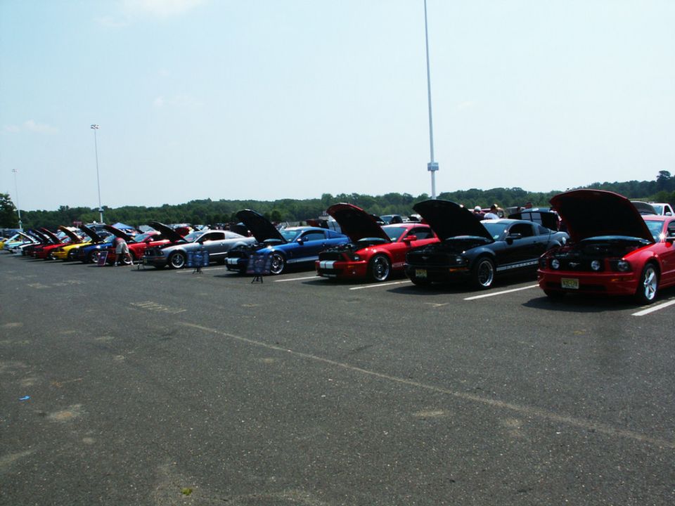 Red and black cars with hoods open at a car show