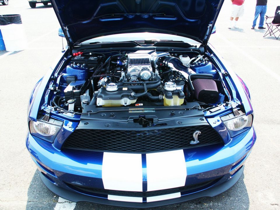 Blue Ford Mustang Shelby GT500 with hood open showing supercharged engine and racing stripes