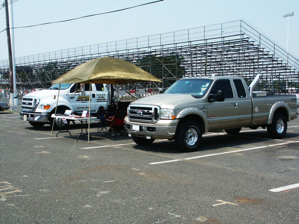 Two Ford Super Duty trucks and a vendor tent in front of bleachers