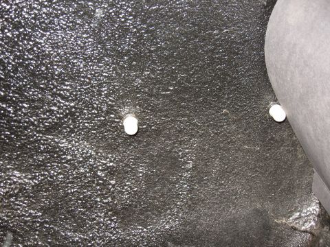 1968 Shelby GT500 - Close-up of the trunk floor showing two white plastic fasteners against a textured black surface.