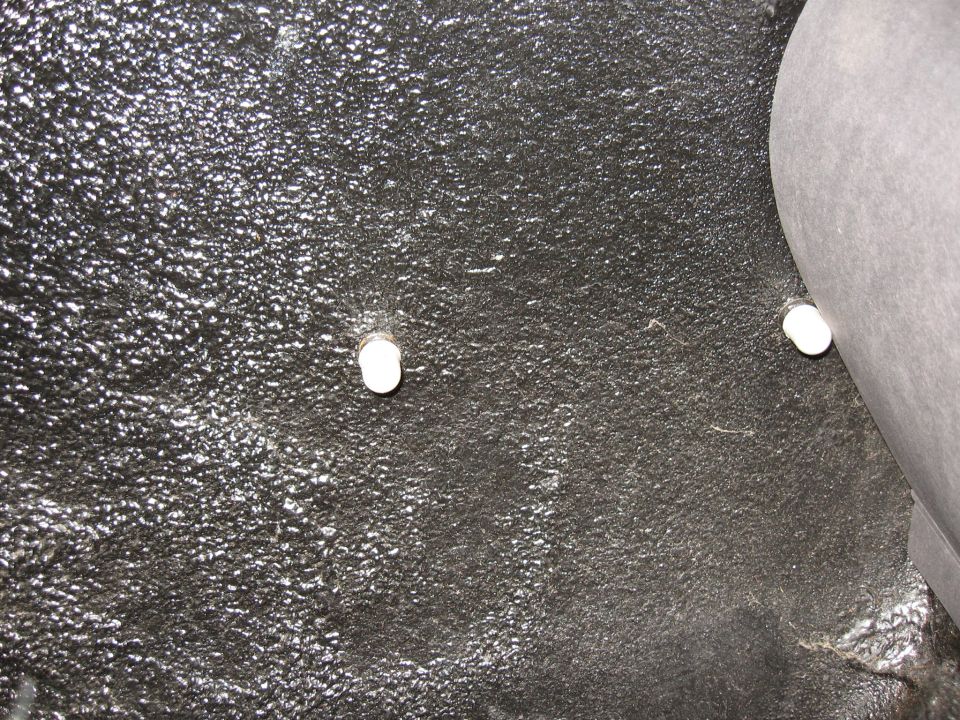 Trunk floor with textured black coating and two white plastic fasteners visible