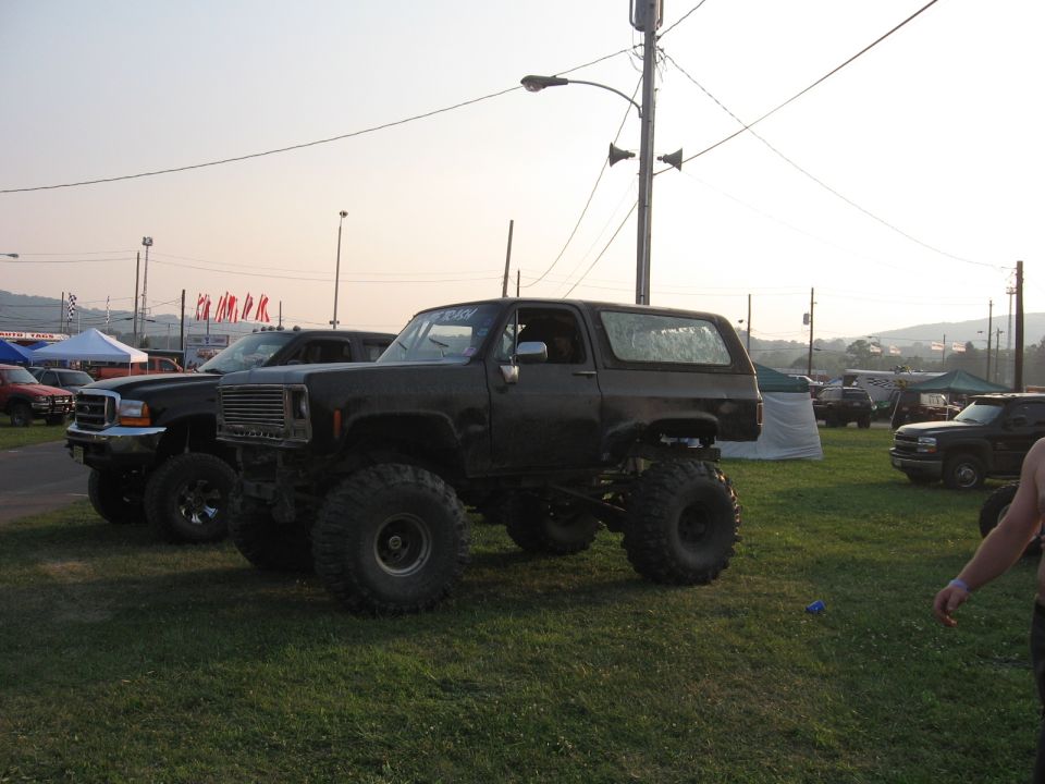 Dark lifted SUV with large tires parked on grass, front grille visible